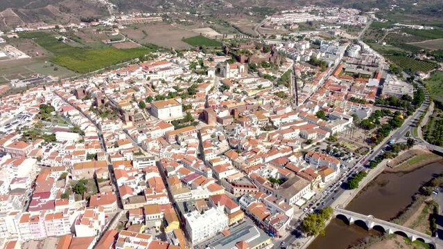 Cinematic aerial perspective of Silves City. Situated in South of Portugal, in Algarve Region. Panoramic view of the city with church and castle in top of the hill. Drone forward and tilt down