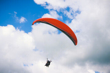 Paraglider flying in cloudy sky