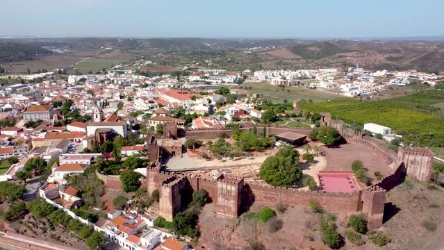 Aerial perspective of Castelo de Silves. Situated in Silves city, Algarve Region in south of Portugal. Beautiful Portuguese village, travel destination. Drone backward and ascending. 