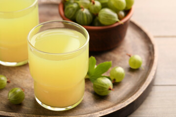 Tasty gooseberry juice and fresh berries on wooden tray. Space for text