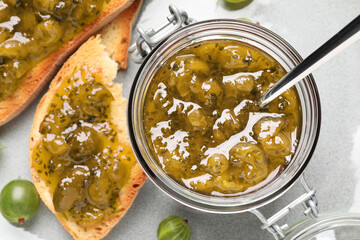Toasts with delicious gooseberry jam and fresh berries on plate, flat lay