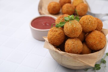 Bowl of delicious fried tofu balls with pea sprouts and sauce on white tiled table, closeup. Space for text