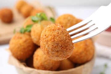 Taking delicious fried tofu ball with fork from bowl, closeup