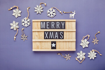 Letter board with text Merry Xmas with christmas decor on violet background. Flatlay.