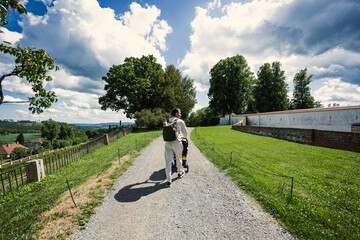 Naklejka premium Back of father with baby carriage walking at Chateau Kunstat, Czech Republic