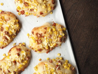 top view corn and ham mayo bread bun on baking tray on wooden table