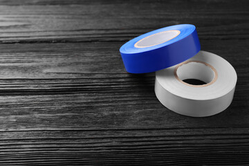 Colorful insulating tapes on black wooden table. Space for text