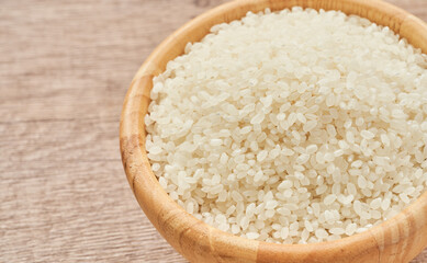 heap of short grain rice in wood bowl on wooden table background                                                            
