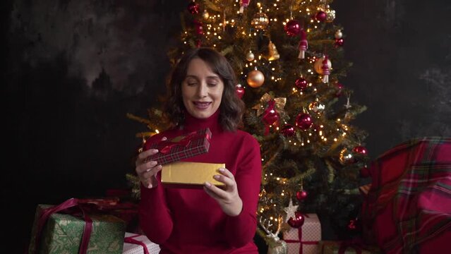 woman with disappointment opening box with surprise on background of xmas tree