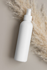 White cosmetic spray bottle mockup with a pampas on the beige background.