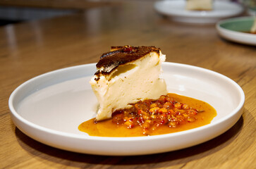 Piece of cheesecake with sea buckthorn jam on a plate