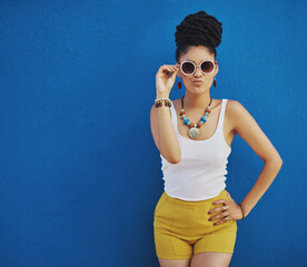 Fashion, summer and black woman with sunglasses on blue background wall in city on weekend. Freedom, beauty and girl enjoy holiday, travel and vacation in urban town with trendy clothes and cosmetics