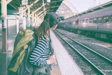 Young asian woman traveler backpack in the train station. Backpacker female at the railway. Travel concept. The concept of a woman traveling alone. Lady traveler tourist