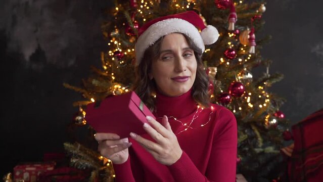 woman looks at a box with a gift, shakes it, tries to guess what is inside