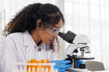 close up, Young woman scientist looking through a microscope in a chemical laboratory. medical...