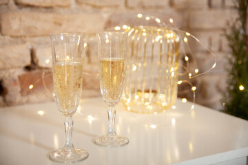 Glasses of champagne. Gold Christmas decor with lights