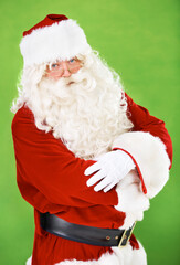 Christmas, santa and costume with a man in studio on a green background for festive season celebration. Portrait, glasses and serious attitude of saint nick standing arms crossed for the holidays