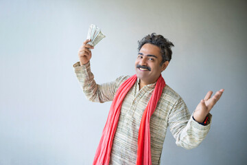 Indian farmer showing money and giving happy expression.