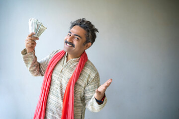 Indian farmer showing money and giving happy expression.