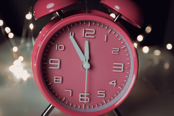 Obraz na płótnie Canvas Pink alarm clock with bokeh background. Count down time clock for celebrating happy new year.