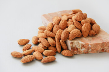 Small grains of natural brown almonds on a marble stone on a gray background