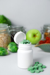 Obraz na płótnie Canvas Bottle of prebiotic pills and food on grey table