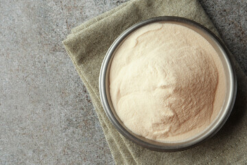 Bowl of agar-agar powder on grey table, top view. Space for text