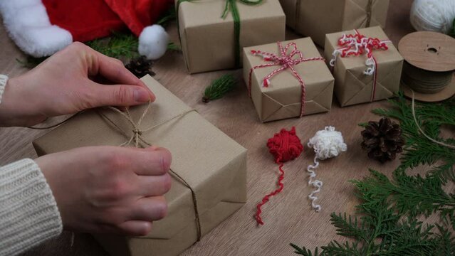 woman's hands preparing a gift box Christmas present using recycled wrapping paper