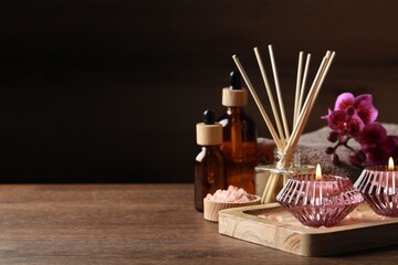 Beautiful spa composition with different care products and burning candles on wooden table. Space for text