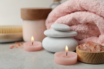 Beautiful composition with burning candles and different spa products on light grey table, closeup