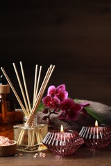 Beautiful spa composition with different care products and burning candles on wooden table