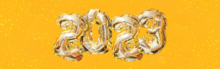 Helium golden balloon number of year 2023. Glowing festive garland with bokeh on orange background. Happy New Year banner