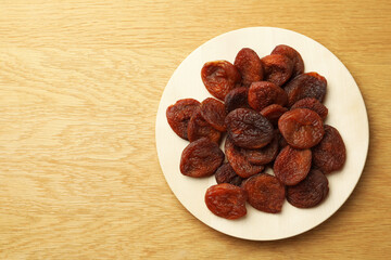 Plate of tasty apricots and space for text on wooden table, top view. Dried fruits
