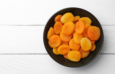 Plate of tasty apricots and space for text on white wooden table, top view. Dried fruits