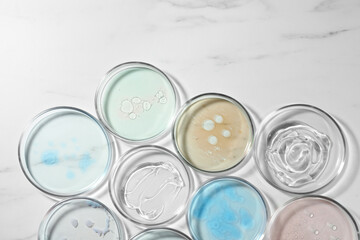 Petri dishes with liquids on white marble table, flat lay
