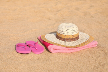 Fototapeta na wymiar Beach towel with straw hat and slippers on sand