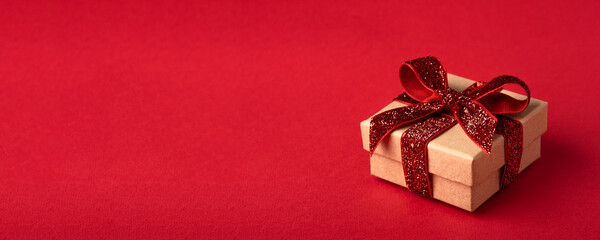 Christmas gift box with red bow on red background.