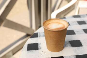 Takeaway paper cup with hot coffee on table outdoors, space for text