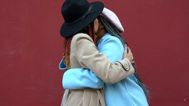 Happy african mother and adult daughter hugging together during winter vacation in the city - Family love concept
