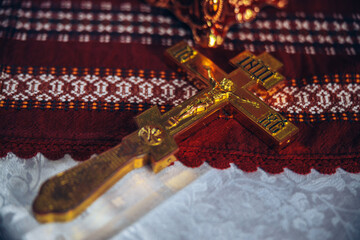 Golden cross on a red and white cover background in the holy church for a child's orthodox baptism christening. High quality photo