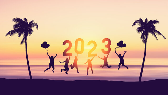 Silhouette friends jumping and holding number 2023 on sunset sky abstract background at tropical beach. Happy new year and holiday celebration concept.