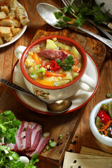 Pea soup with smoked ribs, breadcrumbs and pickled tomatoes on a wooden table