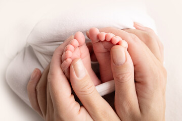 Mother is doing massage on her baby foot. Close up baby feet in mother hands on a white background. Prevention of flat feet, development, muscle tone, dysplasia. Family, love, care, and health concept