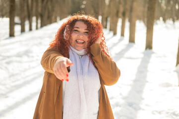 Cheerful fat caucasian woman walks in the park in winter.