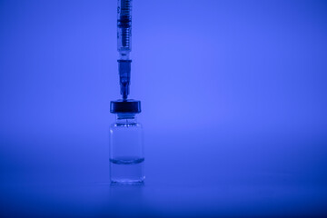 Vaccine vial, syringe with flu shot needle, vaccination medical concept, subcutaneous injection on blue background. Copy space. Test immunization and vaccination laboratory. Healthcare and medicine.
