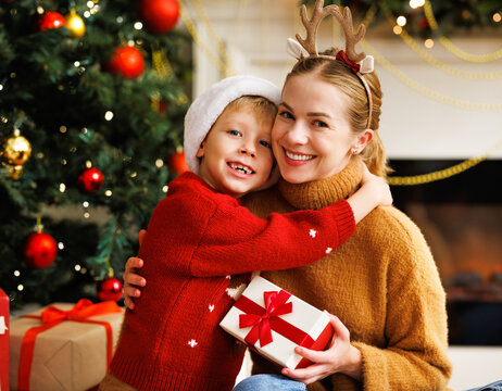 Cute child  smiling embracing and kissing mother opening christmas presents together