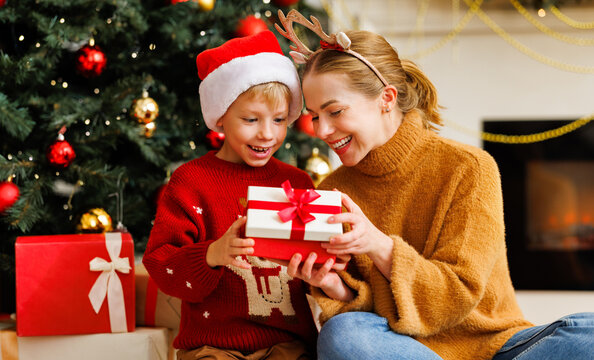 Cute child and smiling mother opening christmas presents together