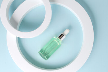 Glass bottle of oil on geometrical round forms. Background for branding and packaging presentation. Natural skincare beauty product concept