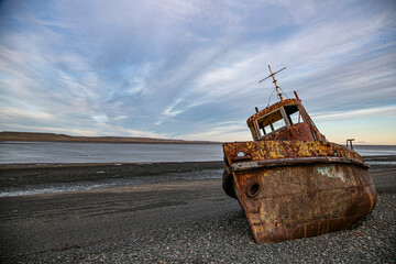 Fototapeta na wymiar Weathered Hull of an Old Tugboat Stranded Along the Patagonian Riverbank