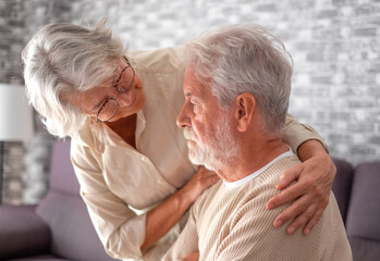 Old worried senior woman comforting her depressed, mental ill husband, unhappy elderly man at home...